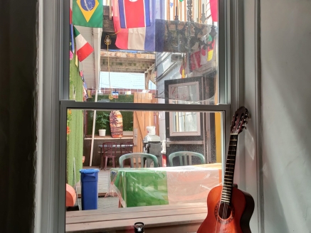 A from inside a hostel window in Quebec CIty, Canada, with a guitar, a water bottle and several country flags