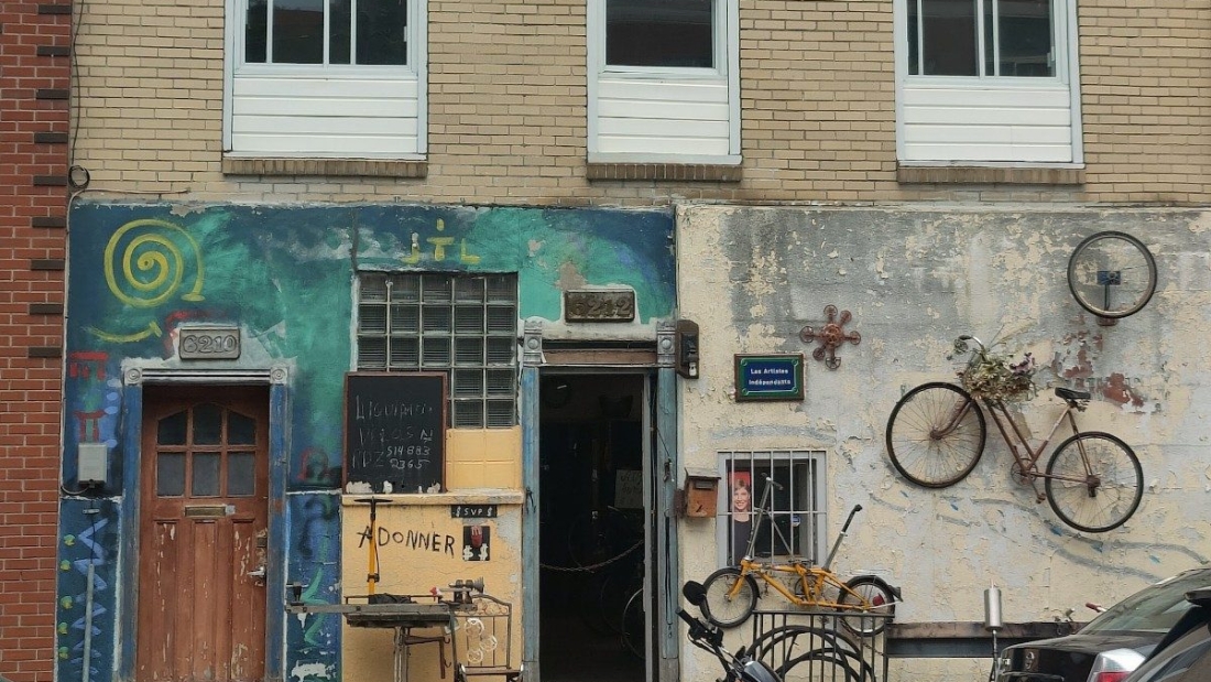 The outside of a bike repair shop, with a motorbike parked out front