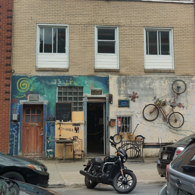 The outside of a bike repair shop, with a motorbike parked out front